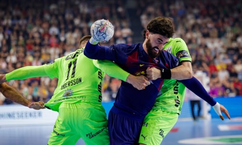 Two handball players compete intensely for the ball during a match, with one in a blue jersey holding the ball while the other in a neon green jersey attempts to block or tackle.